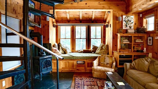 Een gezellig interieur van een chalet met een slaapzolder, een open haard, een bank en een eethoek.