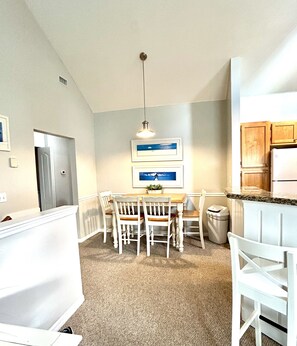 A compact kitchen with white cabinetry, a built-in refrigerator, a dining table with chairs, and a hanging pendant light. - Clean, Comfortable, Family Friendly Condo, EXCELLENT Location! Mins to DISNEY!!  (Kissimmee)