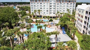 A hotel with a swimming pool surrounded by palm trees and a large building in the background. - Clean, Comfortable, Family Friendly Condo, EXCELLENT Location! Mins to DISNEY!!  (Kissimmee)