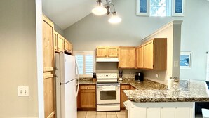A kitchen with wooden cabinets, a white refrigerator, a stove, and a granite countertop. - Clean, Comfortable, Family Friendly Condo, EXCELLENT Location! Mins to DISNEY!!  (Kissimmee)