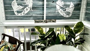 A wooden porch with two decorative panels featuring mermaid designs and a sign that reads "MERMAIDS WELCOME". - Pet friendly cottage 1 block to beach fenced in yard with pergola & outdoor tub (Gulfport)