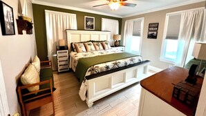 A bedroom with a bed, a desk, a chair, a ceiling fan, and a window. - Pet friendly cottage 1 block to beach fenced in yard with pergola & outdoor tub (Gulfport)