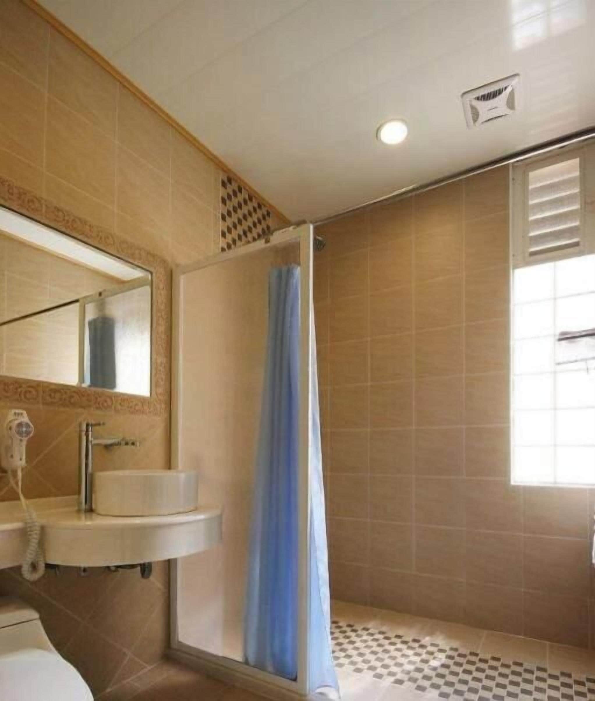 A bathroom with a shower, a sink, a mirror, and a window.