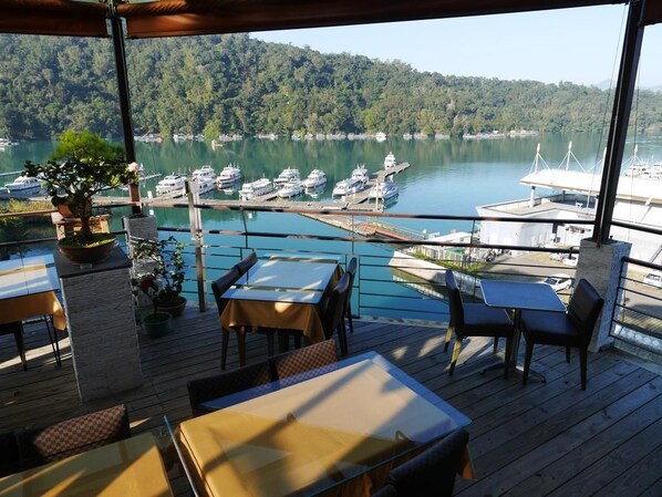A deck with tables and chairs overlooking a marina with boats. - Cherng Yuan Hotel (Yuchi)