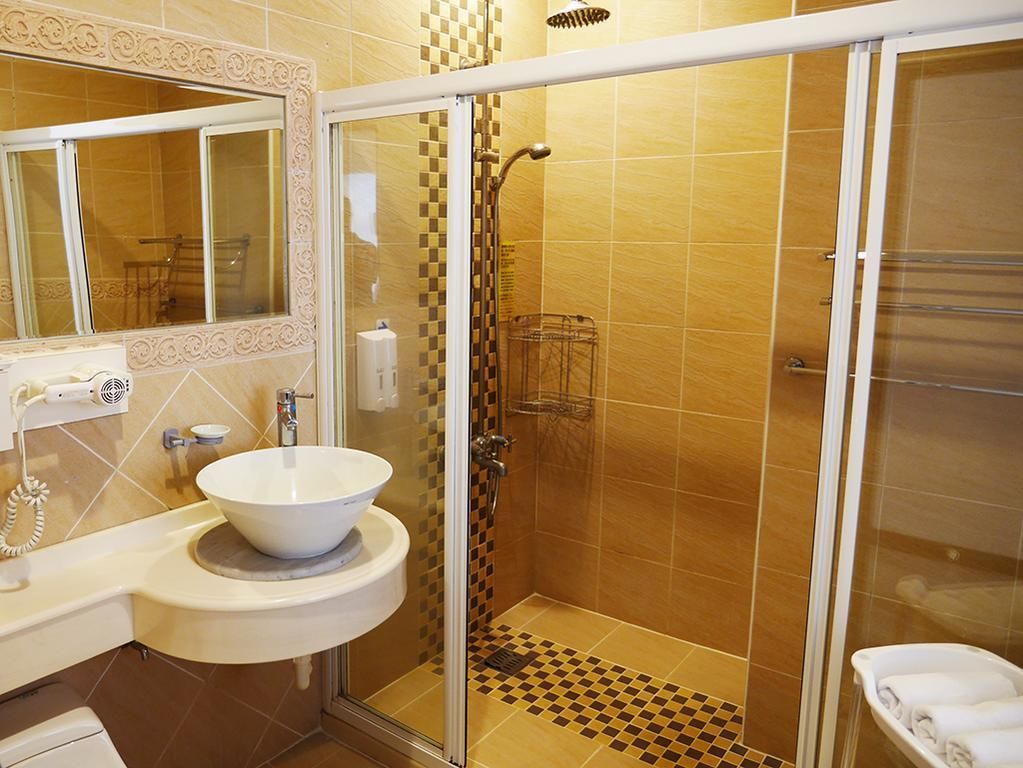 A bathroom with a white sink, a mirror, and a shower area with a glass door.