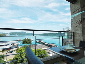 A balcony with a view of a lake, a dock, and a building with solar panels. - Cherng Yuan Hotel (Yuchi)