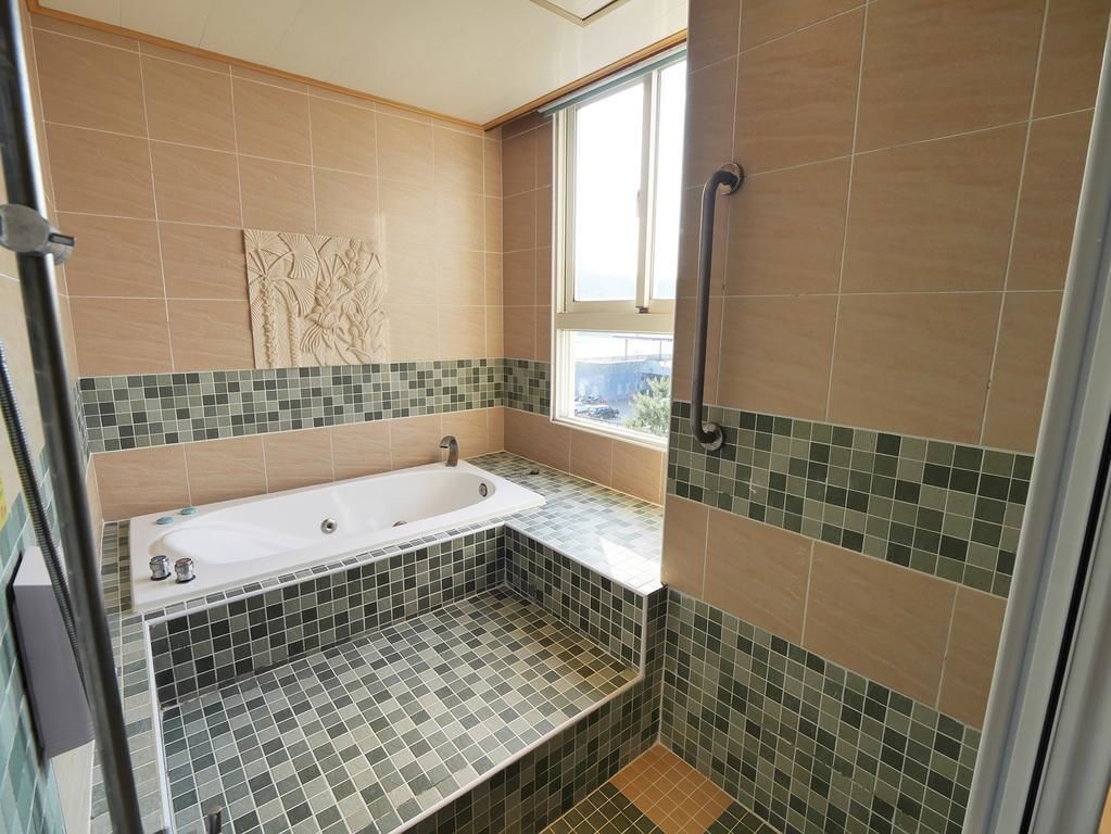 A bathroom with a bathtub, a shower, and a window.