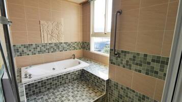 A bathroom with a bathtub, a shower, and a window.