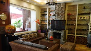 A cozy living room with wicker furniture, a stone fireplace, and a television. - Cherng Yuan Hotel (Yuchi)