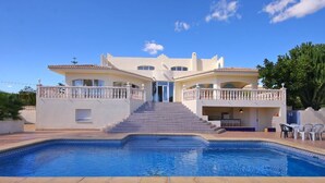 Un'ampia casa con piscina, una scala che conduce all'ingresso e mobili da esterno.