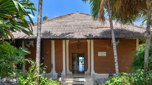 A brick building with a thatched roof, a sign reading "Villa Bungla", and a paved entrance with steps. - Modern, Luxury and Spacious Beach front Villa with Private Pool & Staff (Dencarik / Lovina)