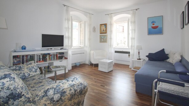 Ein modernes Wohnzimmer mit einer Couch, einem Fernseher, einem Bücherregal und einem Essbereich.