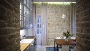 Una cocina con pared de piedra, una mesa de comedor de madera y un jarrón con flores.