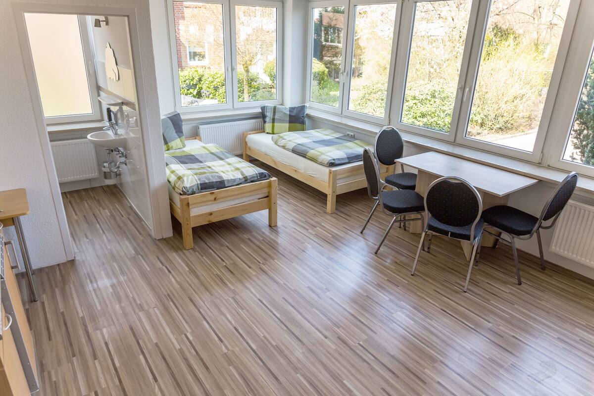 A room with two wooden beds, a small sink, and a table with chairs.
