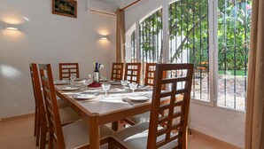 Un espace repas avec une longue table en bois, dressée pour six personnes, entourée de chaises en bois.