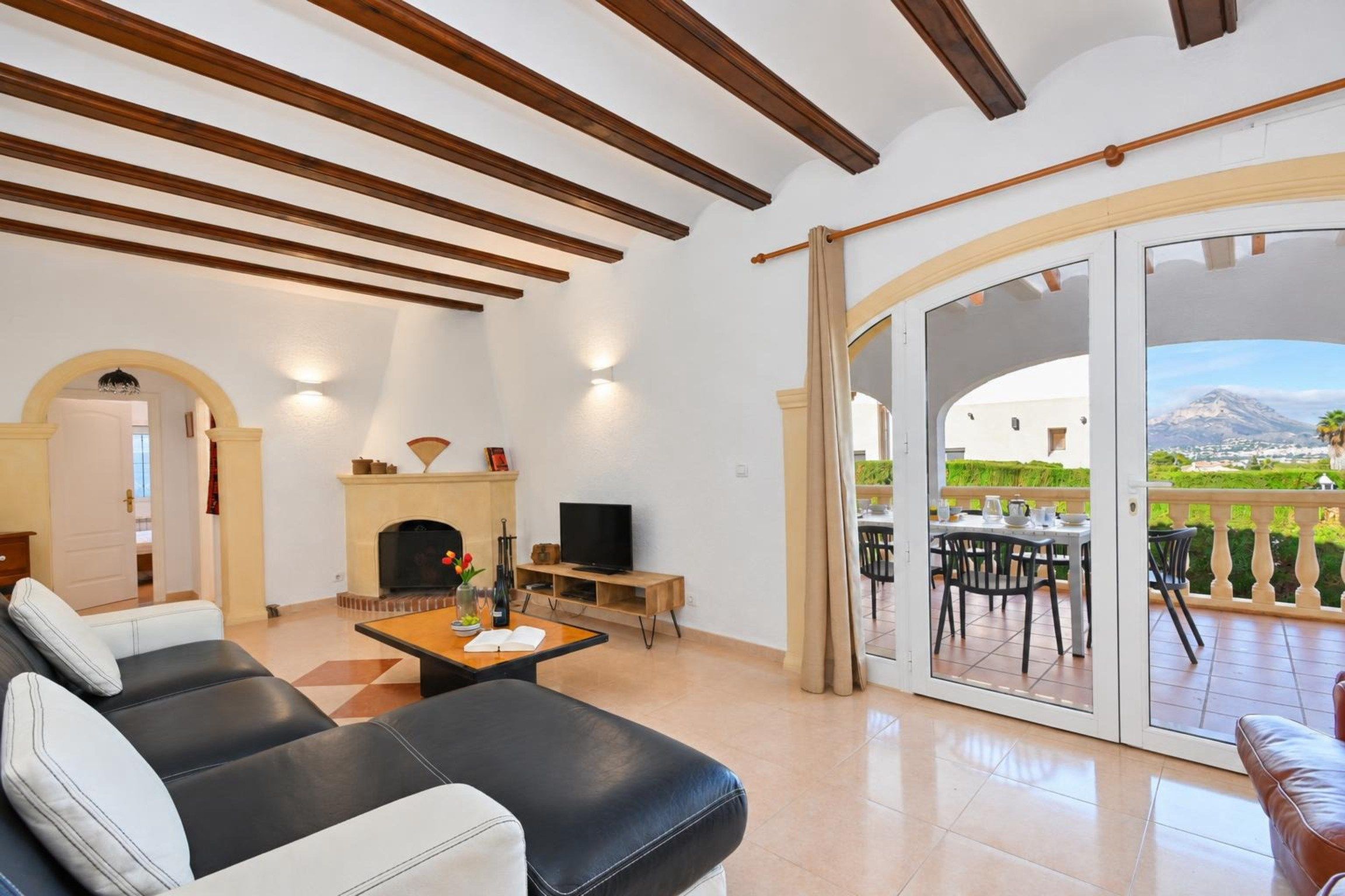 A spacious living room with a fireplace, a television, and a dining area with a view of a mountain.