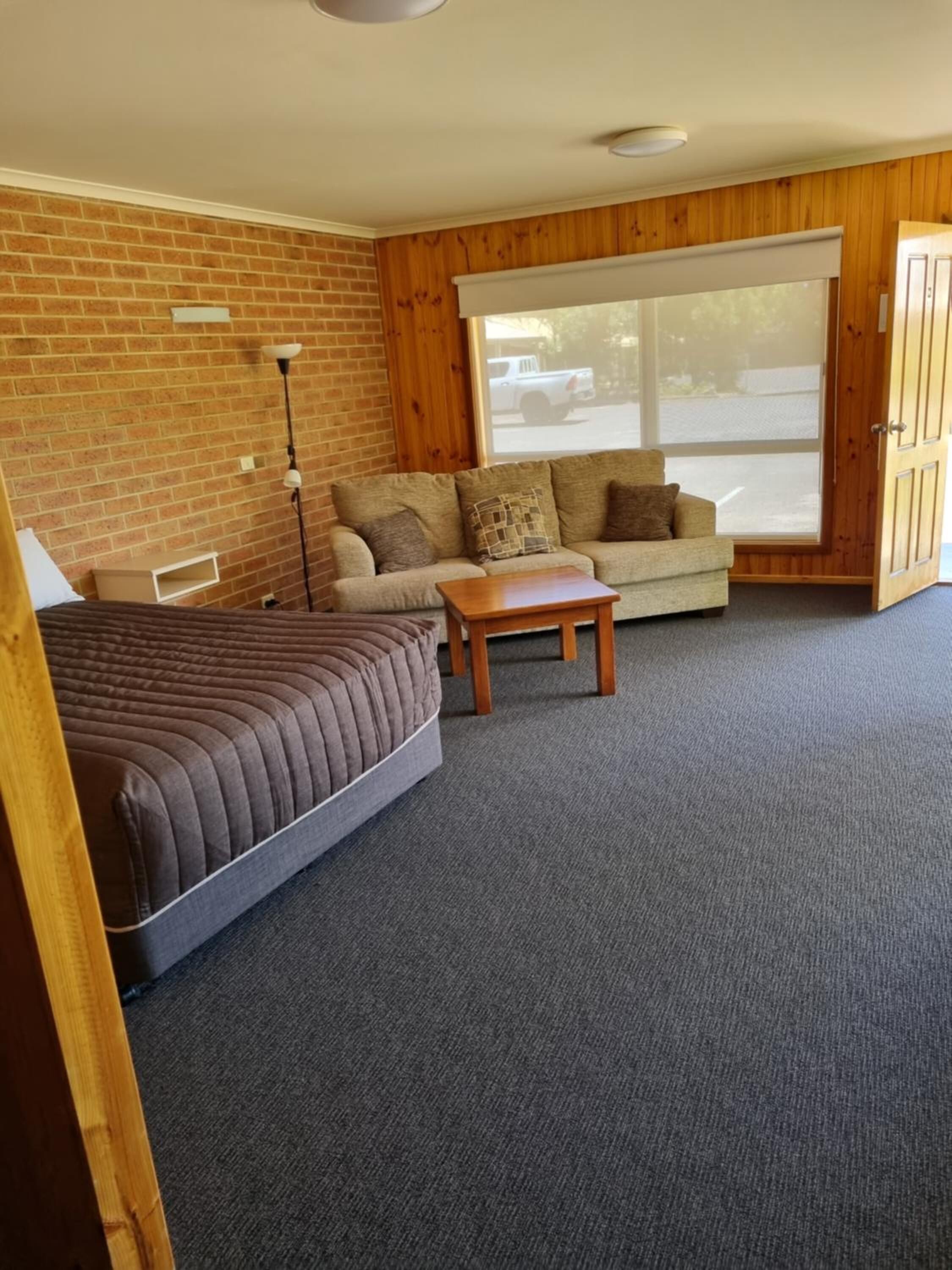 Een kamer met een bed, een slaapbank, een tafeltje en een groot raam.