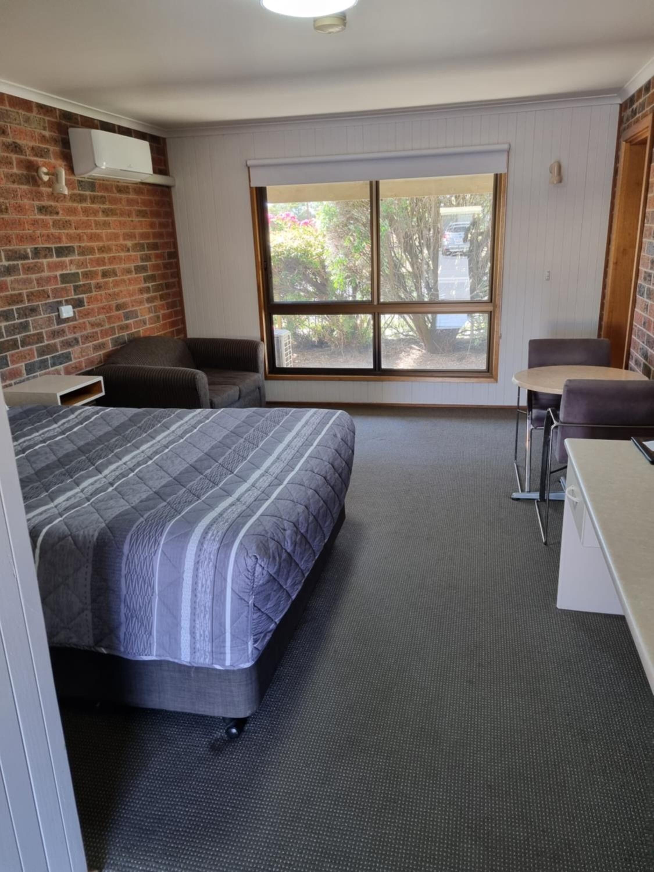 Una habitación con cama, escritorio y ventana.