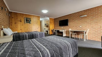 Habitación de hotel con dos camas, un escritorio, una silla, un televisor y una pared de acento de madera.