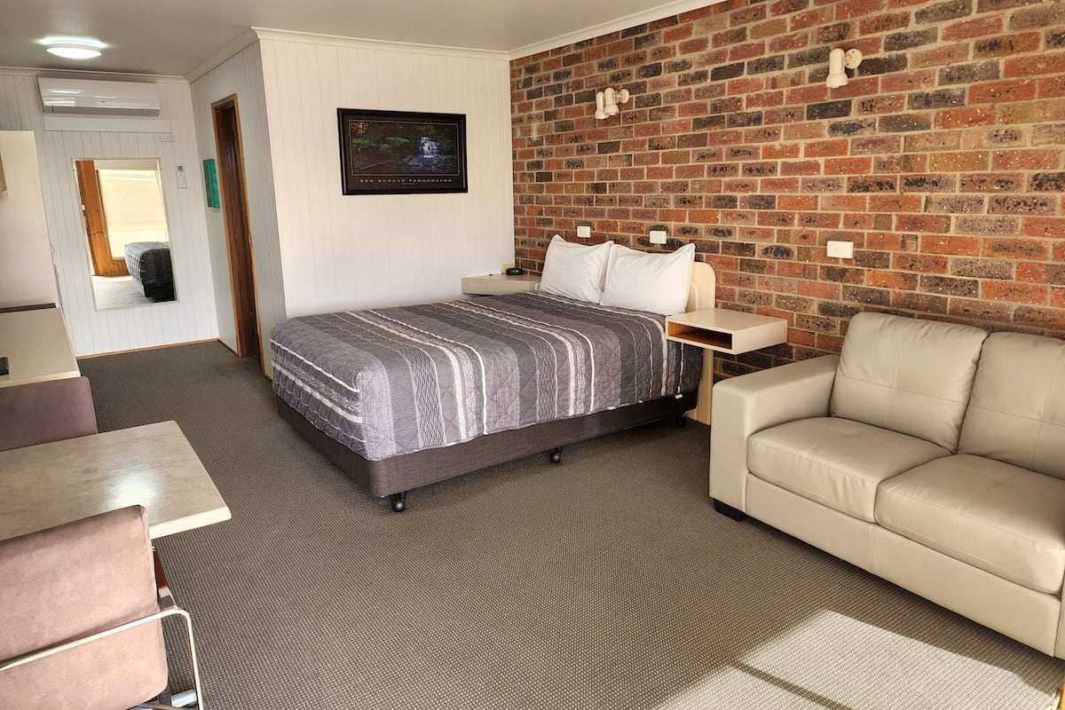 Ein Hotelzimmer mit einem Bett, einer Couch, einem Schreibtisch und einer Ziegelwand.