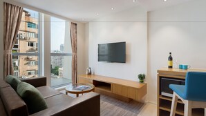 Una sala de estar moderna con sofá, una mesa de centro, televisor y un pequeño comedor con una silla y una mesa.