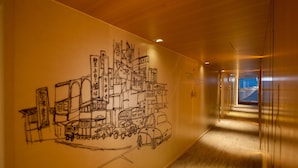Un pasillo con un mural de un paisaje urbano y vehículos.