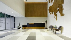Un área de recepción moderna con mostrador, asientos y una pared decorativa.