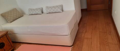 A neatly made bed with a mattress, pillows, and a wooden nightstand.