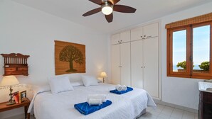 Ein Schlafzimmer mit einem Bett, einem Kleiderschrank, einem Nachttisch mit Lampe und einem Fenster mit Blick.