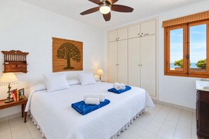 A hotel room with a bed, a wardrobe, a window with a view, and a ceiling fan.