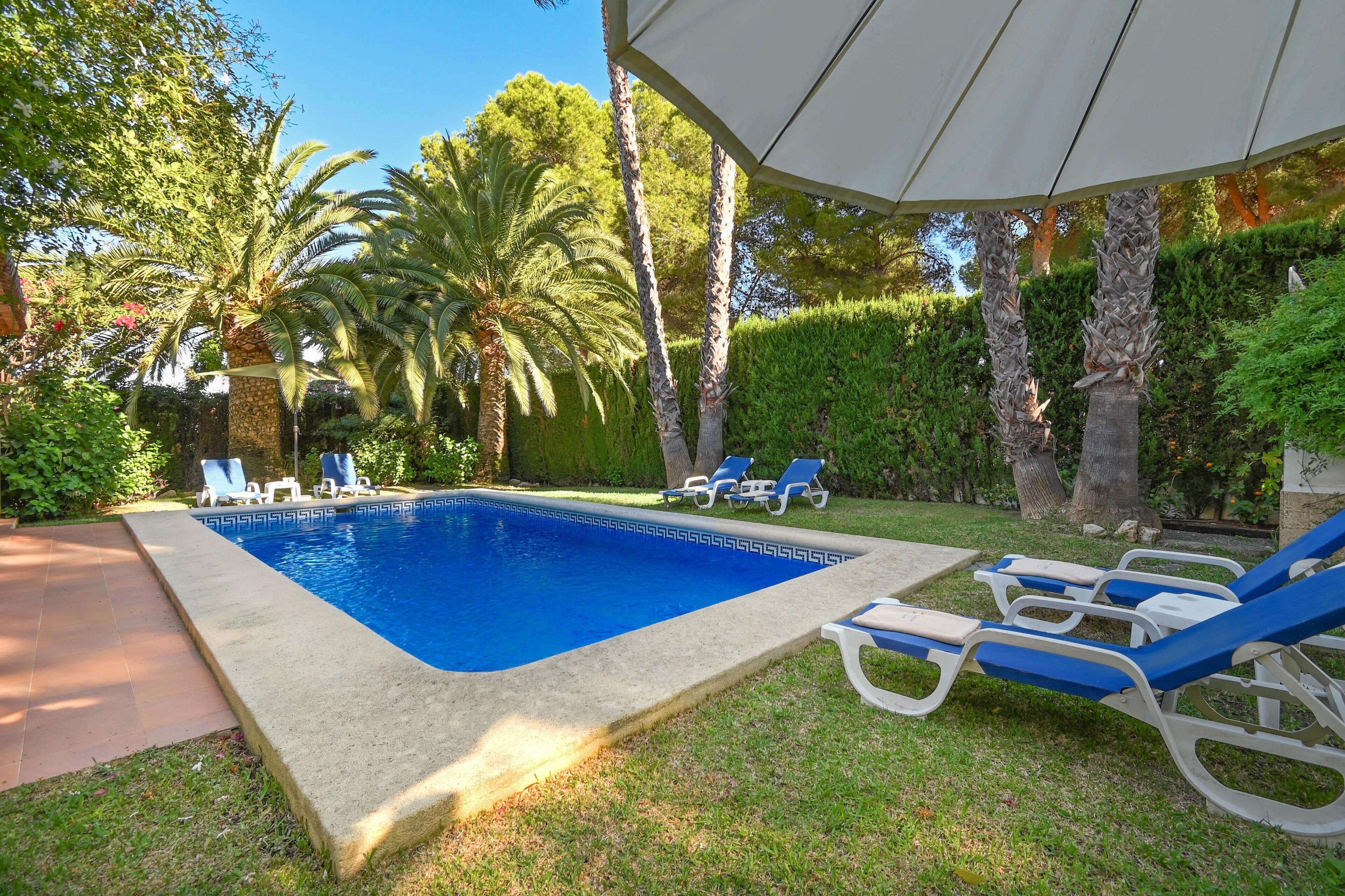 A swimming pool with lounge chairs and a covered area.