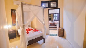 A neatly arranged bedroom with a four-poster bed, a bedside table, and a nightstand. - Villa Bundar: fabulous beachfront villa with pool and with staff! (Dencarik / Lovina)