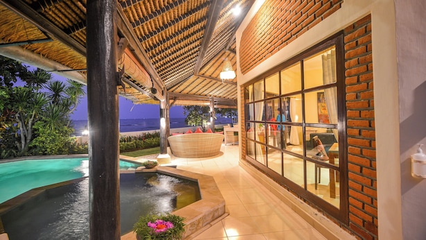 A pool area with a hot tub, surrounded by a covered patio with brick walls and large windows. - Villa Bundar: fabulous beachfront villa with pool and with staff! (Dencarik / Lovina)