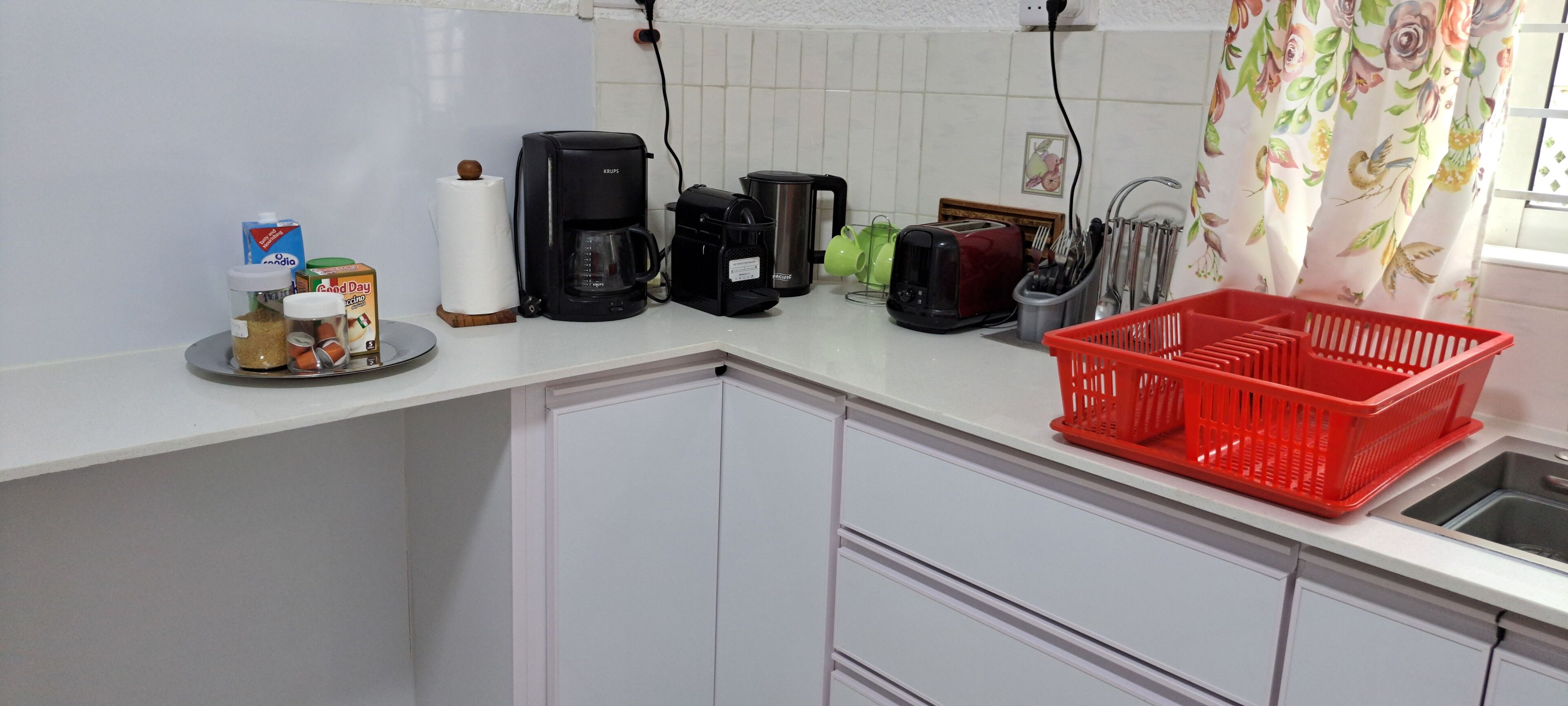 Ett kök med en kaffebryggare, en brödrost och en röd korg på bänkskivan.