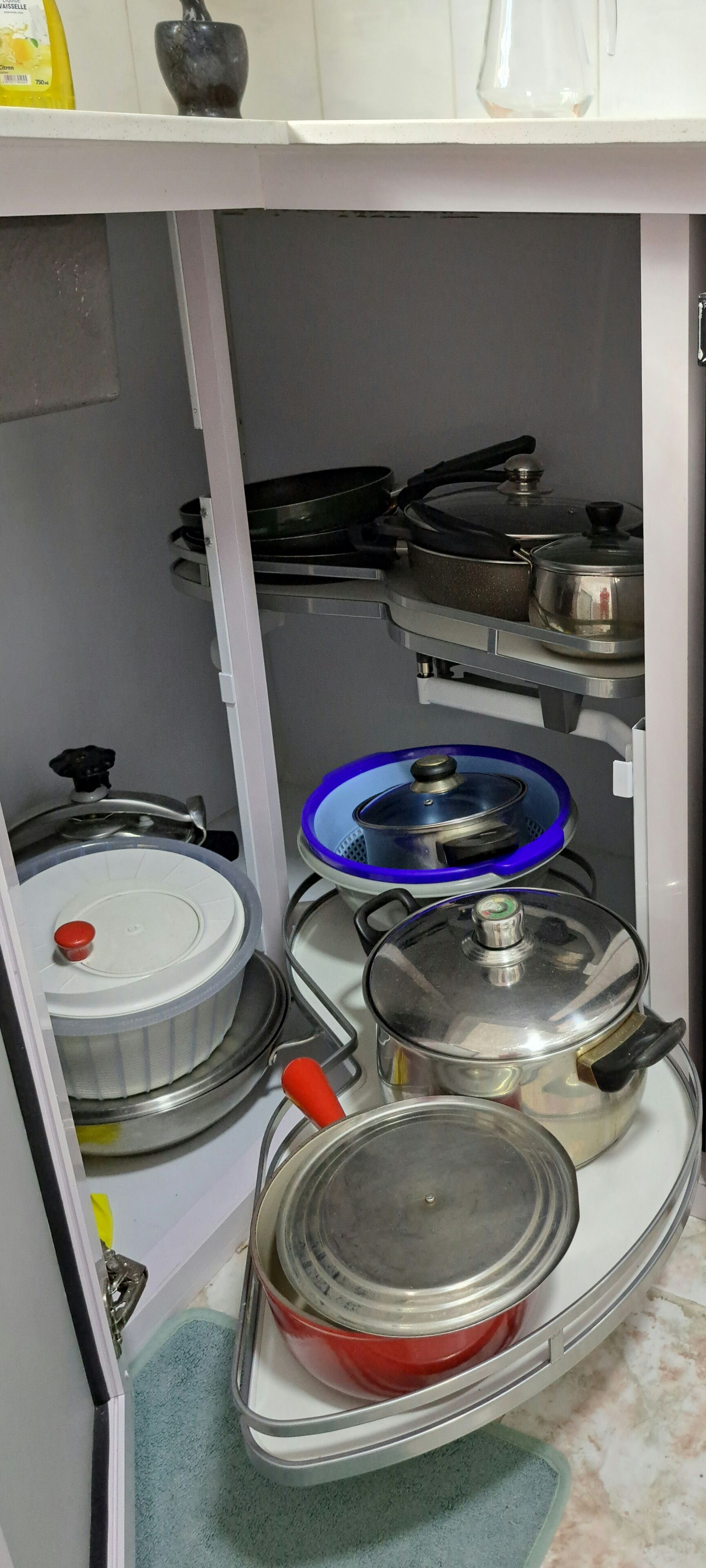 A kitchen with a stove, pots, and pans stored on shelves.