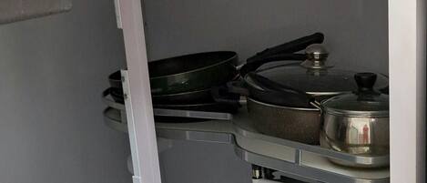 A kitchen with a stove, pots, and pans stored on shelves.