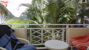 A balcony with a white table and two chairs, one covered with a blue and black checkered towel and the other with a red and orange striped towel. -  A Villa in an idyllic setting, unparalleled service at a cool price (Flic en Flac)