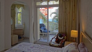A hotel room with a bed, a chair, a small table, a window, and a view of the outside balcony. -  A Villa in an idyllic setting, unparalleled service at a cool price (Flic en Flac)