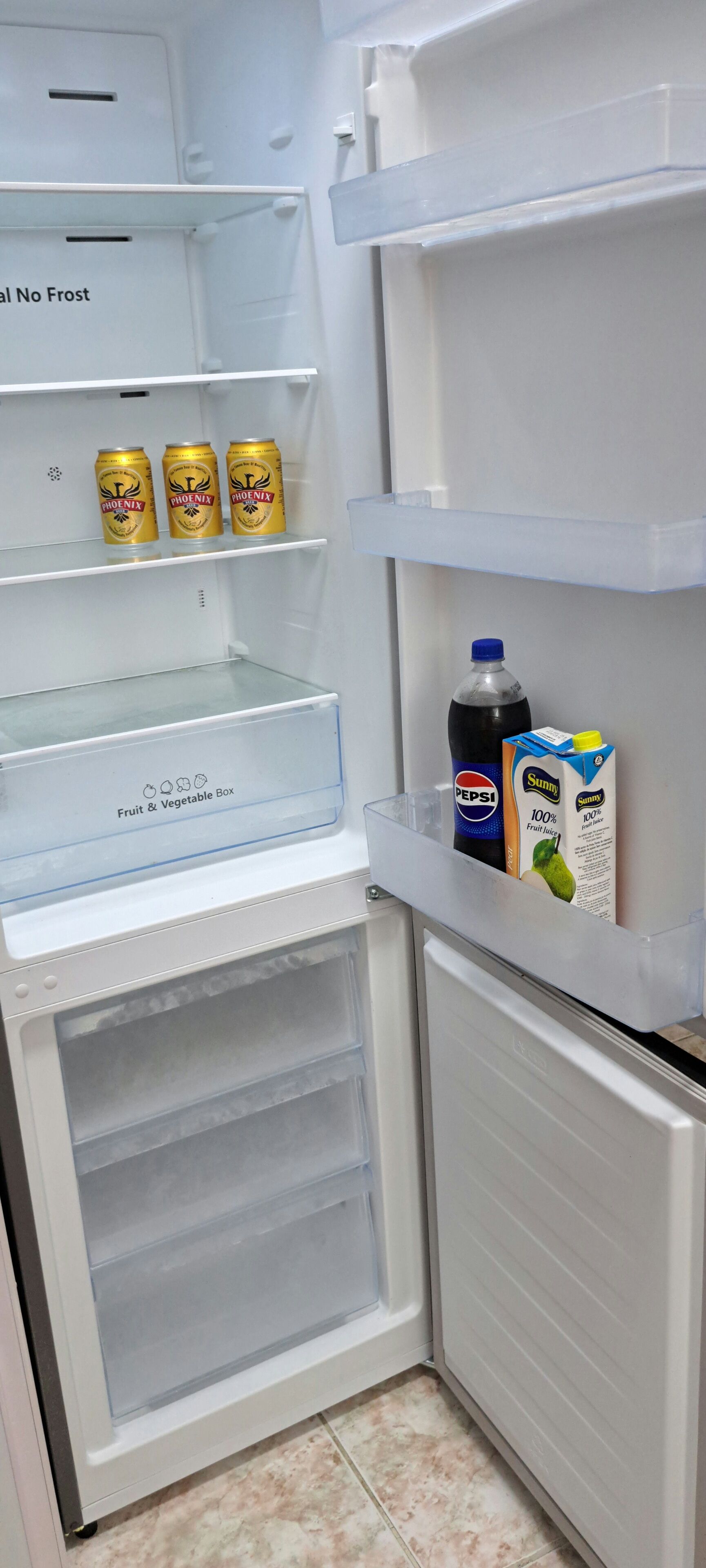 An open refrigerator with a fruit and vegetable drawer, a freezer, and shelves containing beverages.