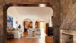 Amplia sala de estar con un arco de piedra, chimenea y televisor.