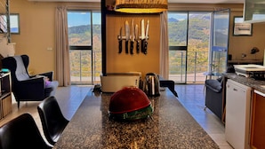 A modern kitchen with a large island, a hanging light fixture, and a view of the mountains through the windows. - Four Storey Finca  Infinity Pool Mountain Views optional separate apartment  (Malaga Province)