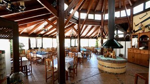 A spacious dining area with wooden tables and chairs, a central decorative island, and a high wooden ceiling with beams. - Four Storey Finca  Infinity Pool Mountain Views optional separate apartment  (Malaga Province)