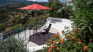 A terrace with a red umbrella, outdoor seating, and a view of the surrounding landscape. - Four Storey Finca  Infinity Pool Mountain Views optional separate apartment  (Malaga Province)