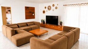 A living room with a sectional sofa, a coffee table, a TV, and decorative wall art.