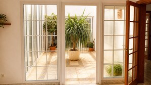 A room with a sliding glass door leading to a tiled patio with potted plants.