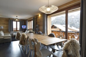 A cozy wooden interior with a large dining table, chairs, and a television in the background. - Apartment/ flat - Chatel (Châtel)