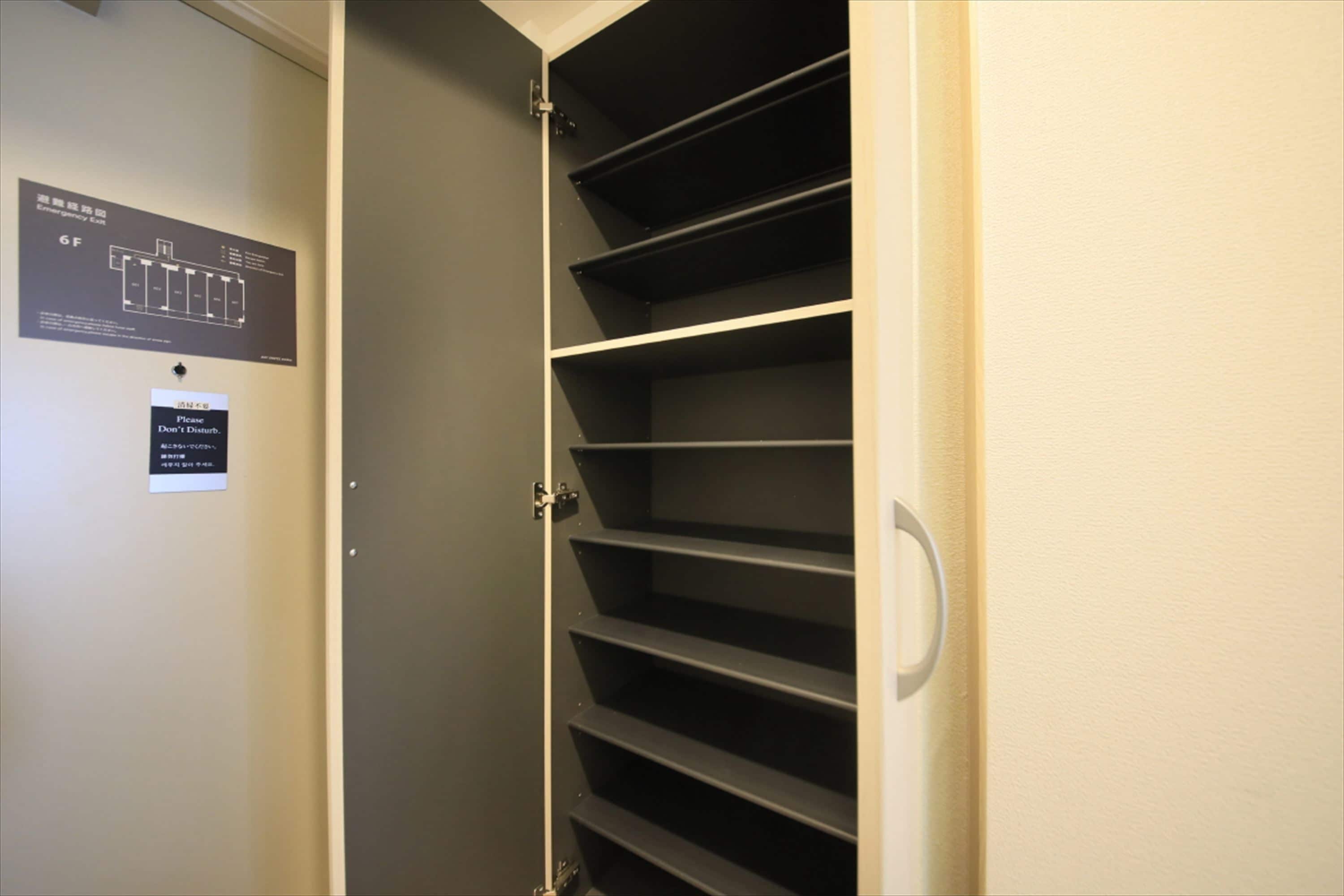 A closed door with a metal handle, a black sign with text and a diagram, and a wall-mounted light switch.