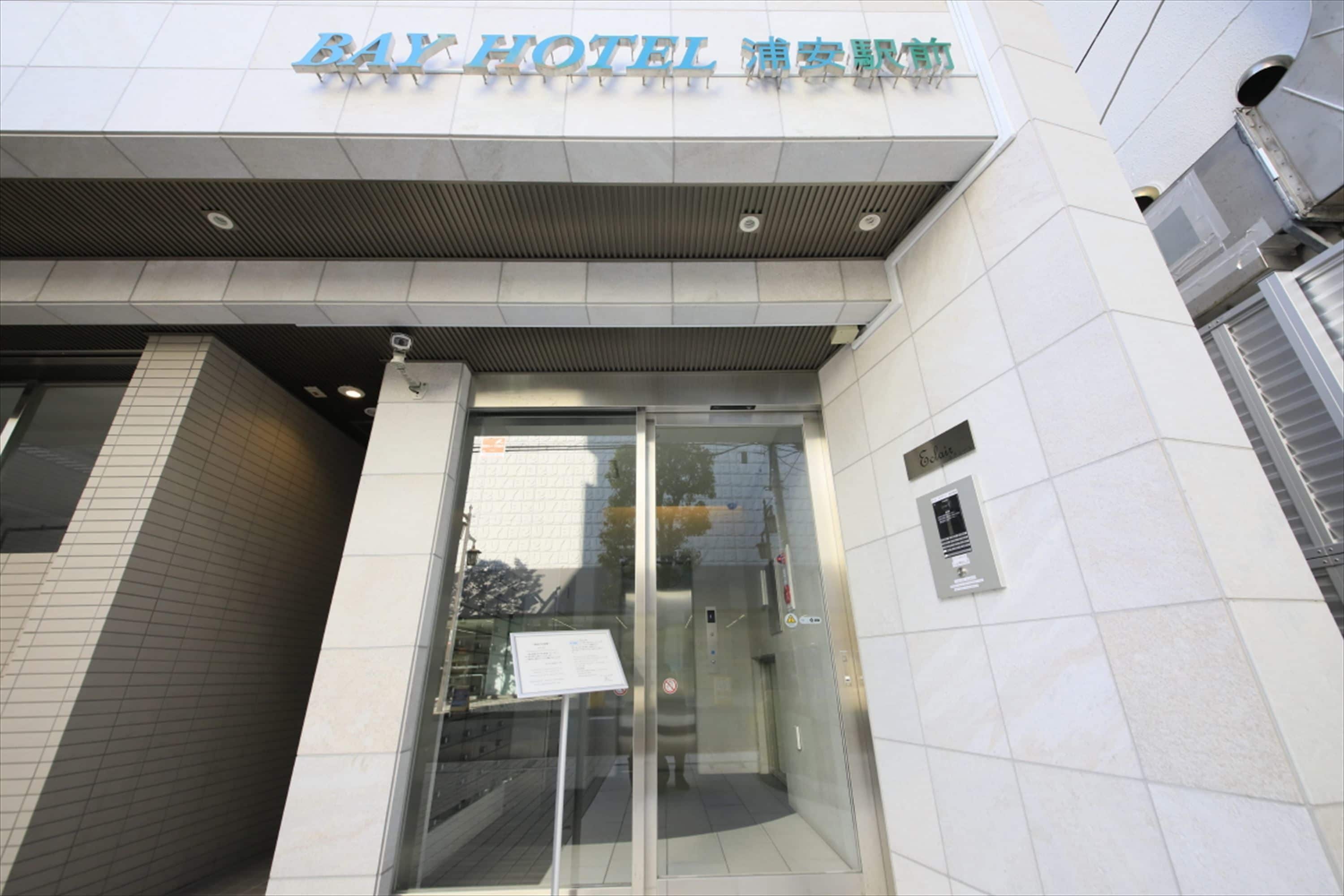 The exterior of Bay Hotel with a modern design, featuring a glass entrance and signage in multiple languages.
