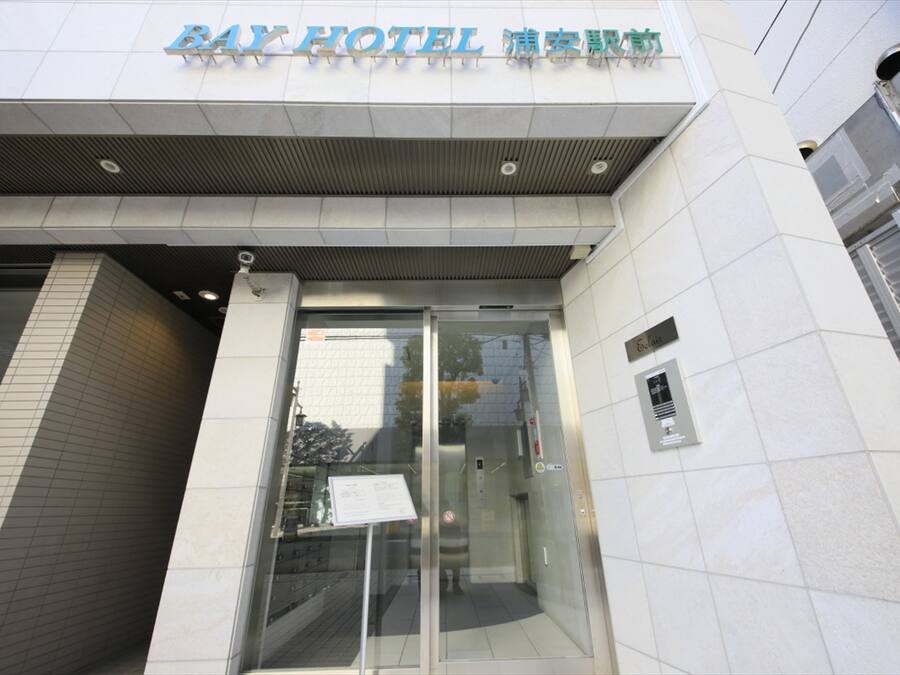 The exterior of Bay Hotel with a modern design, featuring a glass entrance and signage in multiple languages.