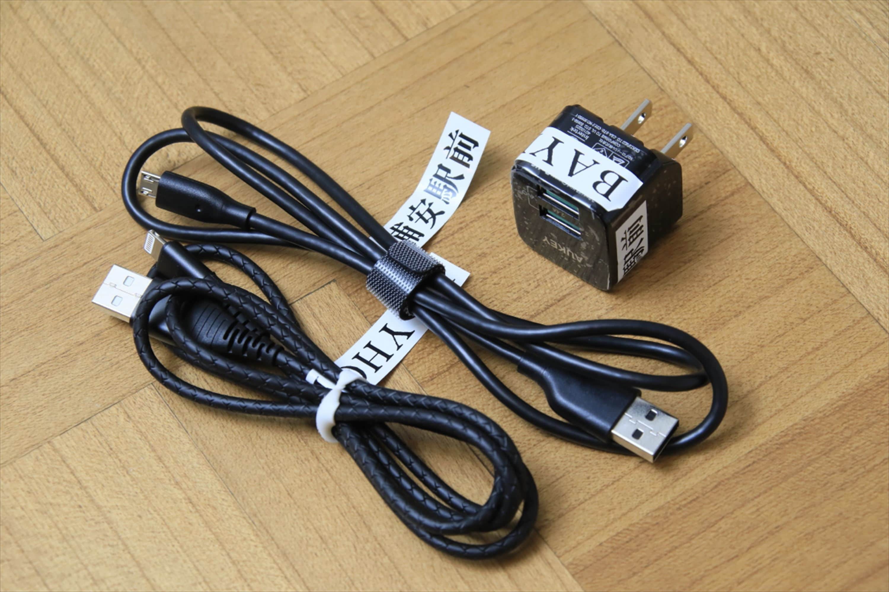 A USB cable and a power adapter on a wooden surface.